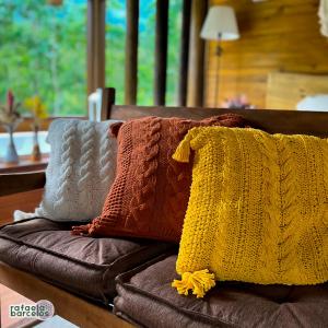 een stapel kussens op een bank met een gele deken bij Vale das Águas Chalé in Treviso