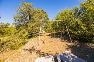 an empty swing set on a hill with trees at Les Villas de Perret in Joyeuse