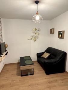 un soggiorno con divano in pelle nera e tavolo di Appart 500 m centre ville - gare a Soissons