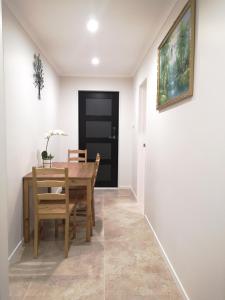 - une salle à manger avec une table, des chaises et une porte noire dans l'établissement Orewa Lovely Cozy Home, à Auckland