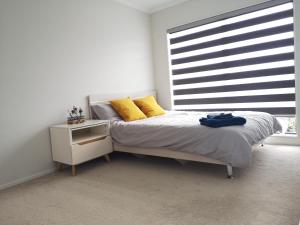 a bedroom with a bed with yellow pillows and a window at Orewa Lovely Cozy Home in Auckland