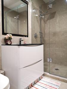 a bathroom with a shower with a sink and a mirror at Orewa Lovely Cozy Home in Auckland