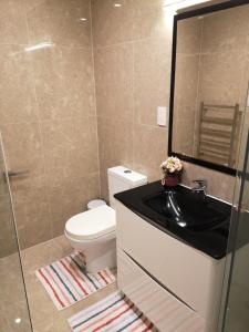 a bathroom with a toilet and a sink and a mirror at Orewa Lovely Cozy Home in Auckland +11 photos