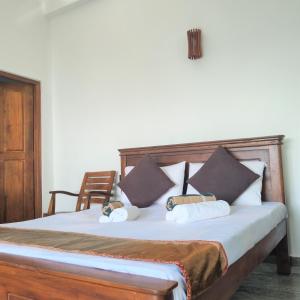 a bed with some pillows and a chair in a room at Dhammika Beach Palace in Wadduwa