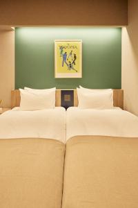 two beds in a room with a green wall at Section L Hatchobori in Tokyo