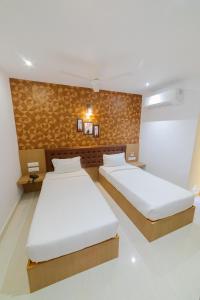 1 dormitorio con 2 camas y pared en Sri K residency en Salem