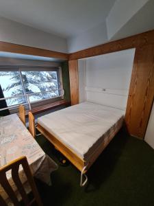 ein Schlafzimmer mit einem Bett und zwei Fenstern in der Unterkunft La casa di Ninis a Marilleva 1400 in Marilleva