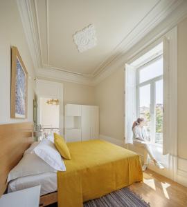 a woman sitting on a window sill in a bedroom at Casa Kala in Porto