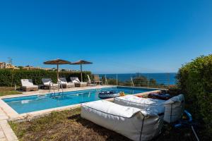 a swimming pool with two couches and umbrellas at Astra Villas in Skala Kefalonias
