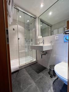a bathroom with a shower and a sink and a tub at Hotel Cresta in Sedrun