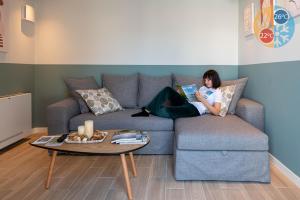 a woman sitting on a couch reading a book at Villa Vesta Retiré - Kalamata Mediterranean Villas in Kalamata