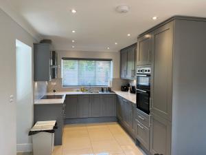 una grande cucina con armadi grigi e una finestra di Pass the Keys Newly built house 4 mins from Twyford Centre a Reading