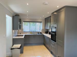 a large kitchen with gray cabinets and a window at Pass the Keys Newly built house 4 mins from Twyford Centre in Reading