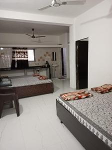 een slaapkamer met 2 bedden en een bureau. bij Ekta Homestay in Garudeshwar