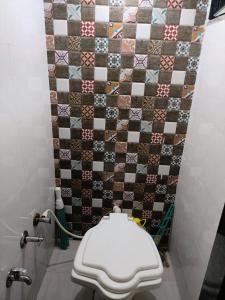 een badkamer met een toilet en een tegelwand bij Ekta Homestay in Garudeshwar