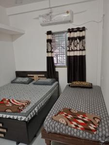 een kamer met 2 bedden en een raam bij Ekta Homestay in Garudeshwar