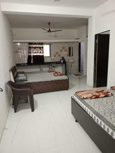 een slaapkamer met 2 bedden en een stoel. bij Ekta Homestay in Garudeshwar