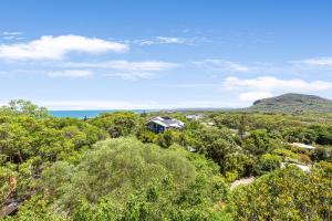 a house in the trees with the ocean in the background at Breathtaking Panoramic Ocean Views in Yaroomba