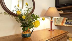 wazon z żółtymi kwiatami na stole przed lustrem w obiekcie Gîte de la Harpe au 4bis w mieście Vauvillers