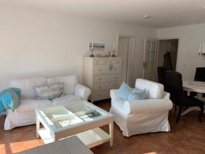 una sala de estar con 2 sofás blancos y una mesa. en Villa Deichhof en Dunsum