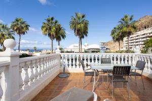 balcón con mesa, sillas y palmeras en Villa Palm Mar en El Palmar