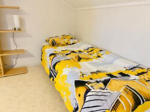1 dormitorio con 1 cama con edredón amarillo y blanco en Central Apartment Närpes en Närpiö