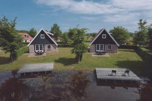 a couple of houses on the water with a dock at Vakantiepark Eigen Wijze in Bant