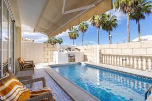 a swimming pool with chairs and palm trees in a house at Villa Palm Mar in Palm-mar