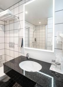 ein Badezimmer mit einem Waschbecken und einem großen Spiegel in der Unterkunft Thon Hotel Kirkenes in Kirkenes