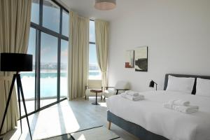 a white bedroom with a bed and a large window at Beach Villas by Olala Homes in Ras al Khaimah