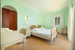 1 dormitorio con cama, escritorio y mesa en Palheiro Village - Golf, Gardens & Spa en Funchal