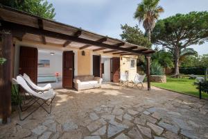 eine Terrasse mit Stühlen und einem Sofa auf einer Steinterrasse in der Unterkunft Villa Adelaide in Villasimius