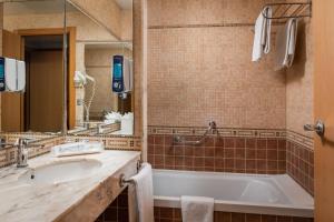 een badkamer met een bad, een wastafel en een spiegel bij Hotel SB Express Tarragona in Tarragona