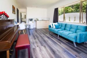 uma sala de estar com um sofá azul e um piano em Farm Stay on Te Awa Cycleway em Tamahere