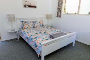 um quarto com uma cama branca e um edredão floral em Farm Stay on Te Awa Cycleway em Tamahere