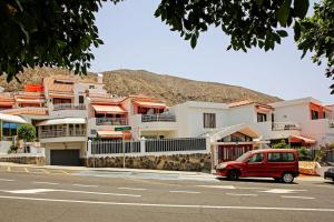 un coche rojo estacionado frente a un edificio en Royal Suite Diamantes I With heated pool, en Los Cristianos