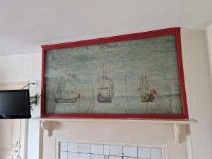 a painting of boats on a wall above a fireplace at The Jolly Sailor, Orford in Orford