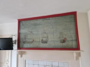 a painting of boats on a wall above a fireplace at The Jolly Sailor in Orford