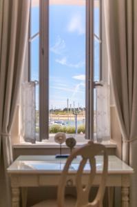 una ventana con una mesa y una silla delante de ella en Hôtel Traiteur Les Ormes, The Originals Relais, en Barneville-Carteret