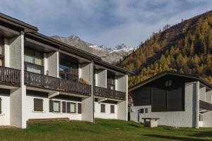 un edificio de apartamentos con balcón y montañas de fondo en La Maison De Montroc - Happy Rentals, en Chamonix-Mont-Blanc