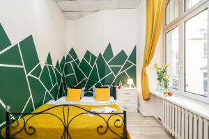 Un dormitorio con una cama amarilla con una pared verde y blanca en Absynt Hostel Wrocław, en Wroclaw