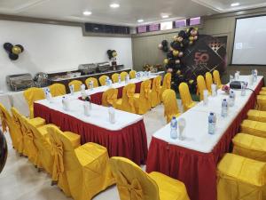 Musada Luxury Hotels and Suites في أبوجا: قاعة اجتماعات مع طاولات وكراسي صفراء
