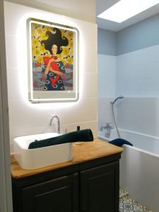 un baño con lavabo y una pintura en la pared en le gîte du fou logement 8 pers 13mn puy du fou en Saint-Amand-sur-Sèvre