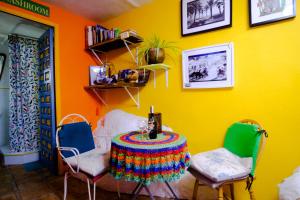 Comares的住宿－The Studio Under The Wall, a colourful, small and unique one bedroom studio in Comares，黄色墙壁的房间里一张桌子和椅子