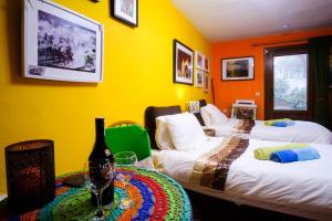 een kamer met 2 bedden en een tafel met een fles wijn bij The Studio Under The Wall, a colourful, small and unique one bedroom studio in Comares in Comares