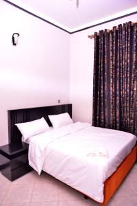 a bedroom with a large bed with a black headboard at Hilltop apartments in Bwebajja