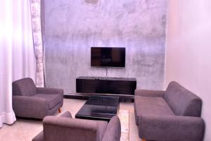 a living room with two couches and a flat screen tv at Hilltop apartments in Bwebajja