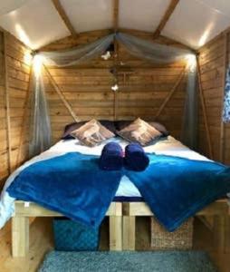 a bed with a blue comforter in a room at Woodland Glamping Cabin in Hatherleigh