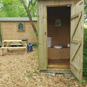 a wooden out house with a toilet in it at Woodland Glamping Cabin in Hatherleigh