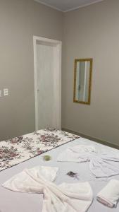 een slaapkamer met een bed met witte lakens en een spiegel bij Pousada Carmel in Ametista do Sul